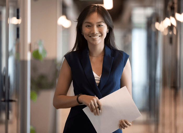 ©Adobstock Fizkes Happy Asian Businesswoman Looking At Camera Stand In Office Hallway (1)