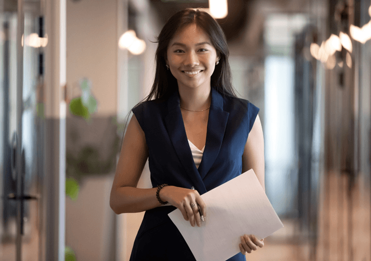 ©Adobstock Fizkes Happy Asian Businesswoman Looking At Camera Stand In Office Hallway (1)